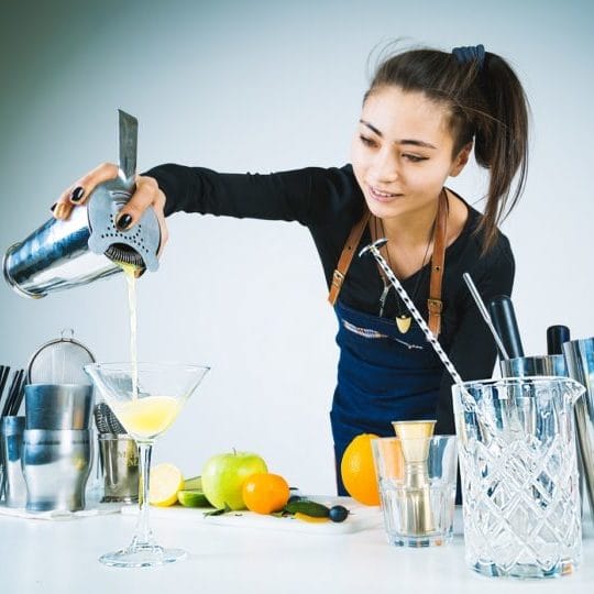 Friends making cocktails together in a home kitchen